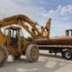 Front loader tractor loading large pipes on a truck