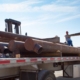 workers unloading large pipes from truck