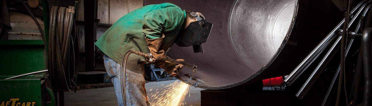 Worker using welding tool on large diameter pipe