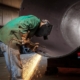 Worker using welding tool on large diameter pipe